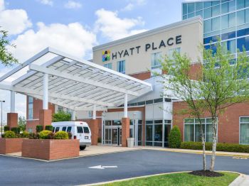 The image shows the entrance of a Hyatt Place hotel with a van parked in front and modern architecture.