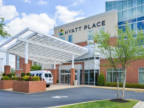 The image shows the entrance of a Hyatt Place hotel with a van parked in front and modern architecture.