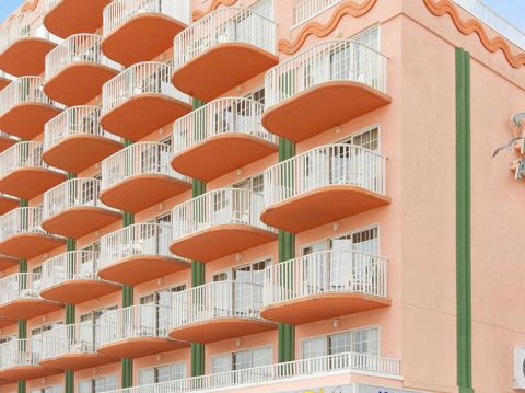 The image shows a multi-story hotel building with numerous balconies and a sign that reads "Paradise" on the facade. The sky is clear and blue.