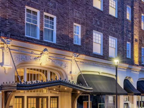 The image shows the exterior of a historic hotel with the name "Virginian Hotel" displayed on a vertical sign, featuring ornate architectural details.