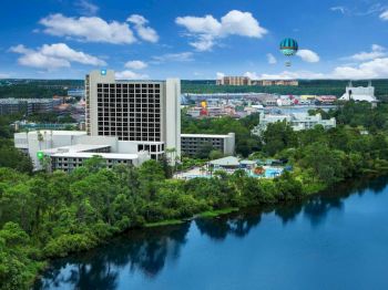 The image shows a scenic view of a large hotel near a lake, with a balloon in the sky and various buildings in the background.